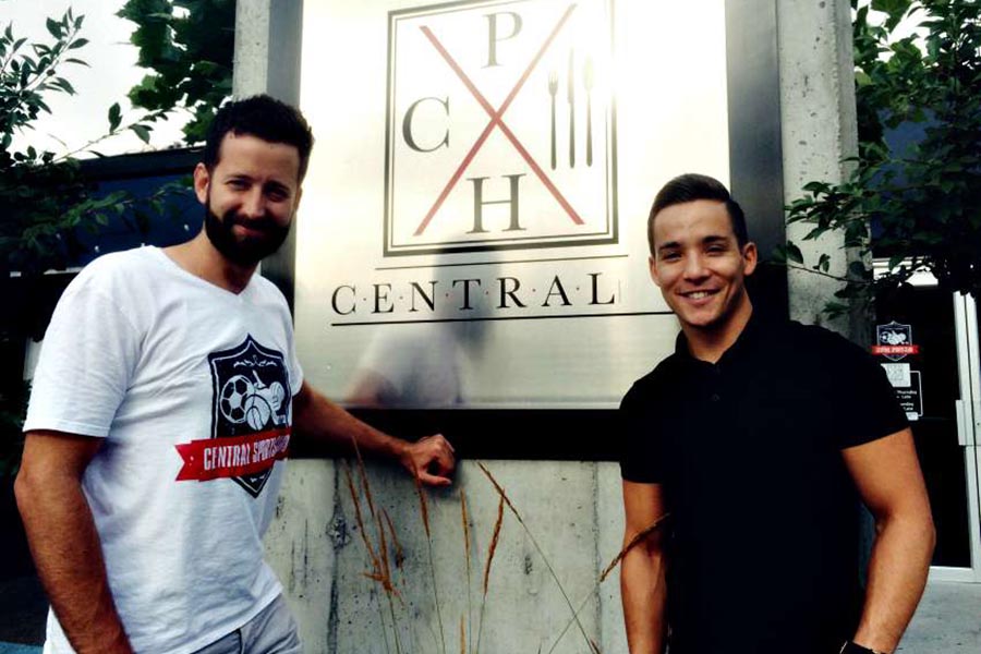 The 2 owners of Central Kitchen + Bar standing infront of their business signage.